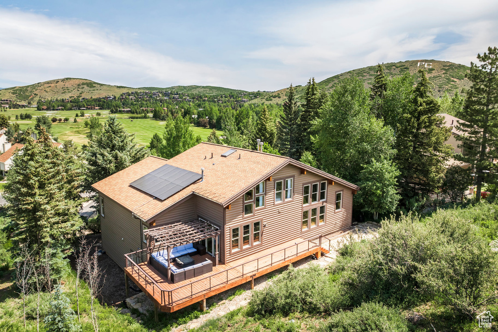 Rear view of house with a shingled roof, solar panels, and a deck with mountain view