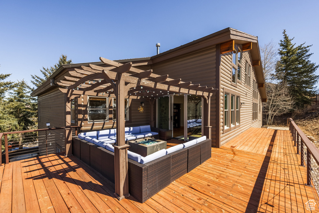 Wooden deck featuring a pergola and an outdoor living space with a fire pit