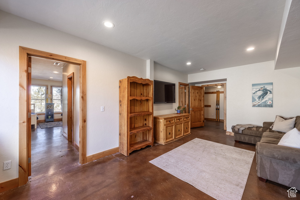 Living area with baseboards, recessed lighting, and concrete flooring