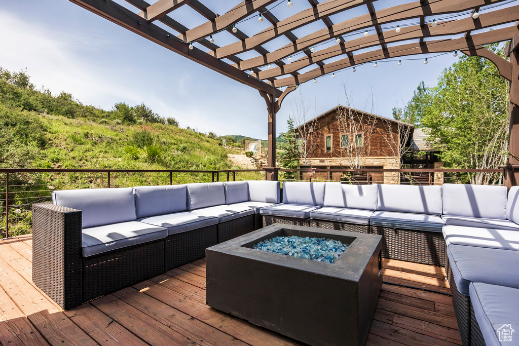 Wooden deck with an outdoor living space with a fire pit and a pergola
