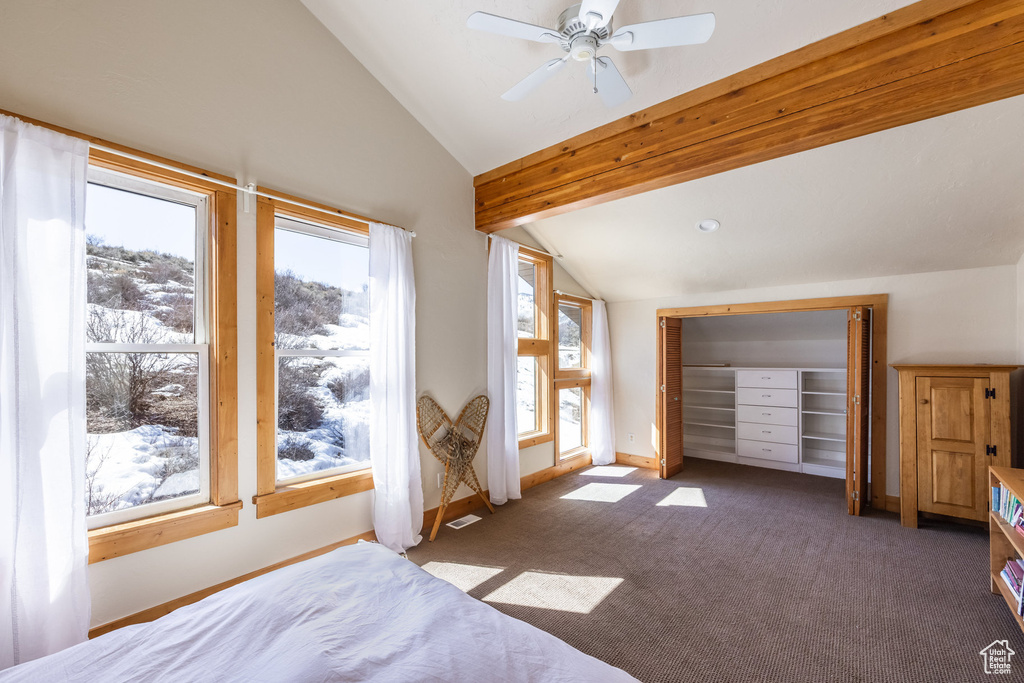 Carpeted bedroom featuring baseboards, ceiling fan, and vaulted ceiling with beams