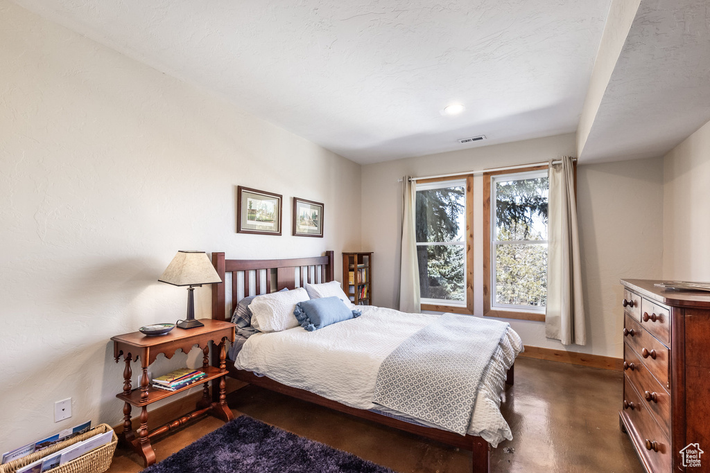 Bedroom featuring visible vents, baseboards, and finished concrete floors