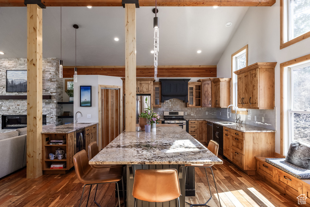 Kitchen with dark wood-style flooring, a sink, brown cabinetry, stainless steel appliances, and a kitchen island