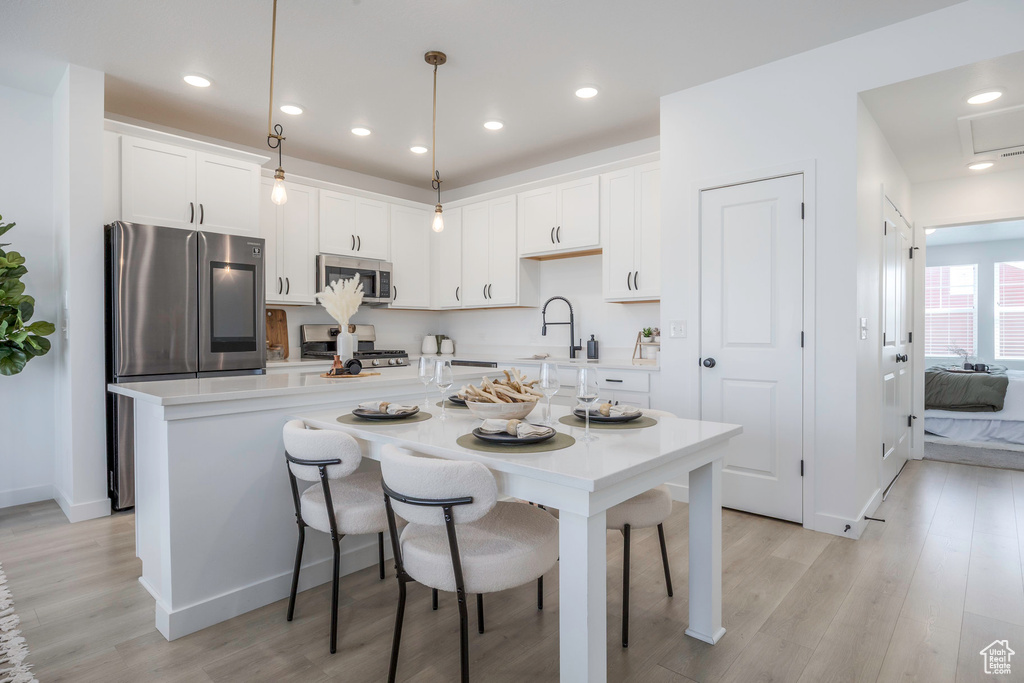 Kitchen featuring light countertops, light wood-style floors, white cabinets, and appliances with stainless steel finishes