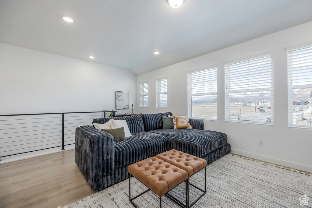 Living area featuring baseboards, lofted ceiling, light wood-style floors, and recessed lighting