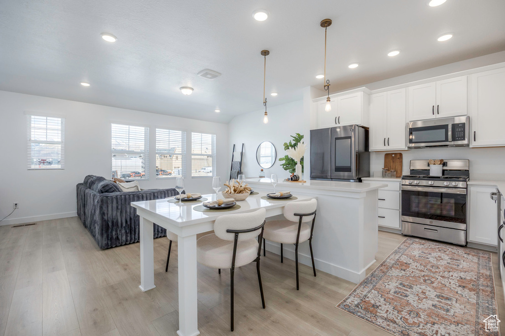 Kitchen featuring white cabinetry, a wealth of natural light, stainless steel appliances, and light wood finished floors