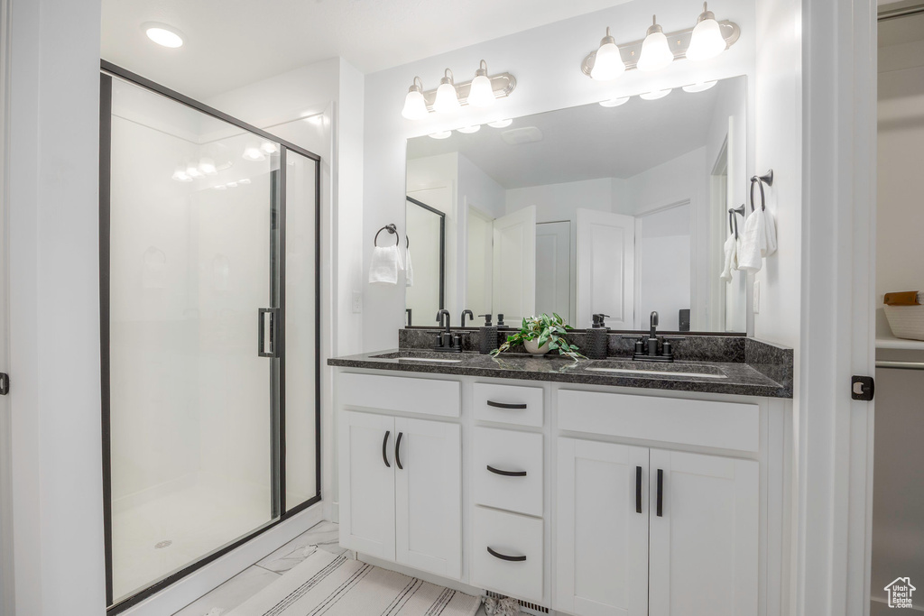 Full bathroom featuring a stall shower, double vanity, marble finish floor, and a sink