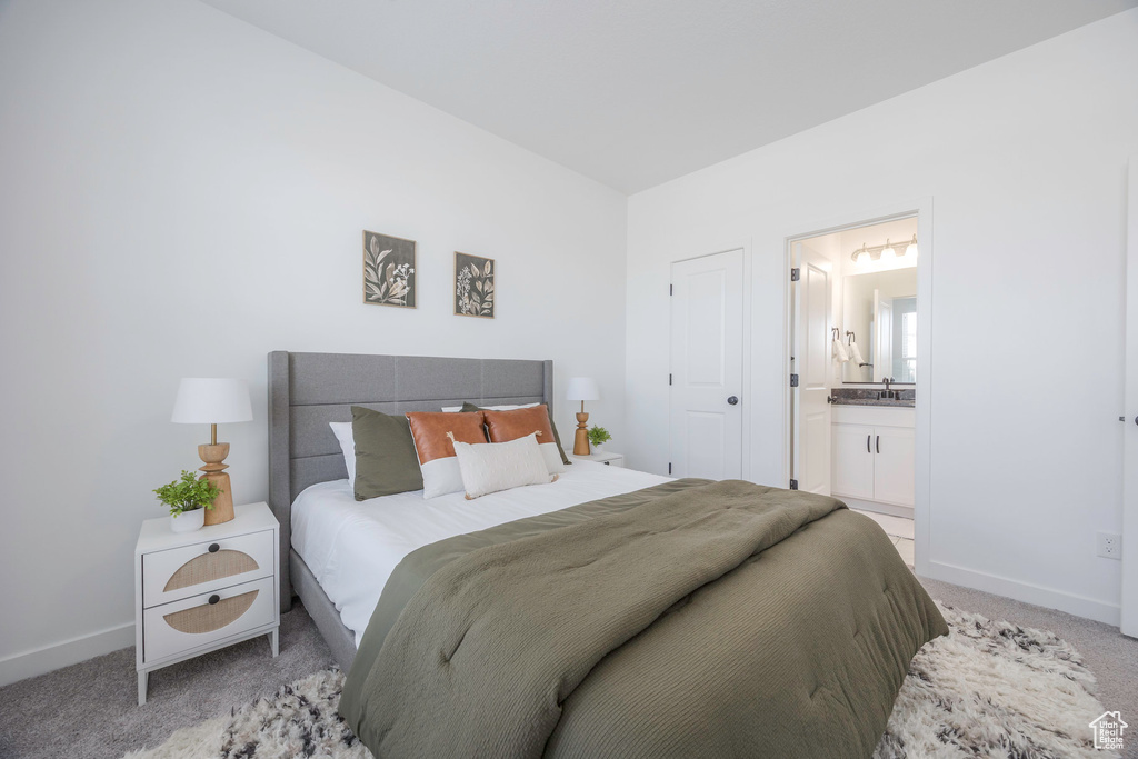 Bedroom with a sink, ensuite bathroom, baseboards, and light colored carpet