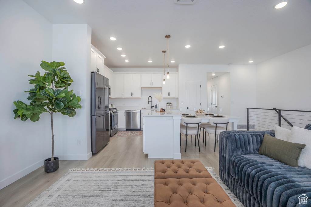 Living area with baseboards, light wood-style floors, and recessed lighting