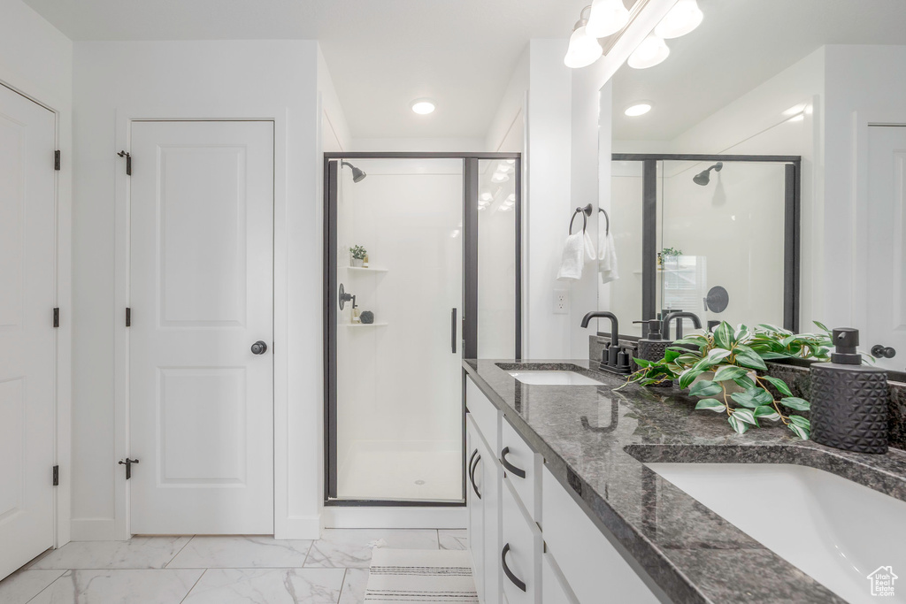 Full bath featuring marble finish floor, double vanity, a stall shower, and a sink