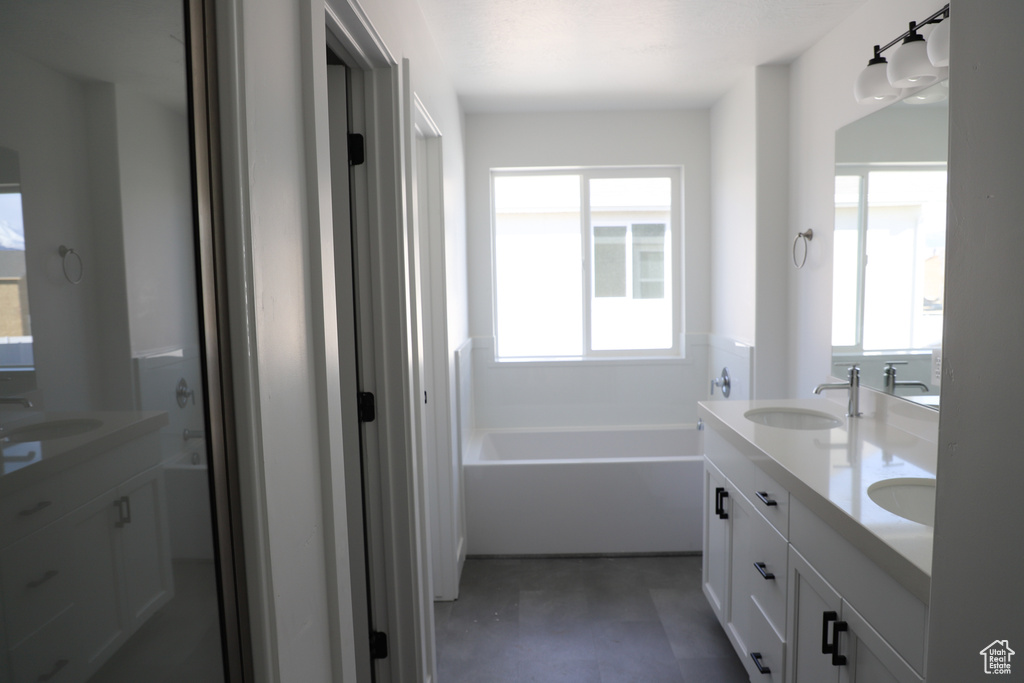 Bathroom featuring a bath, double vanity, and a sink