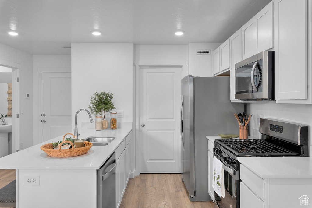 Kitchen featuring light countertops, a sink, appliances with stainless steel finishes, a peninsula, and visible vents