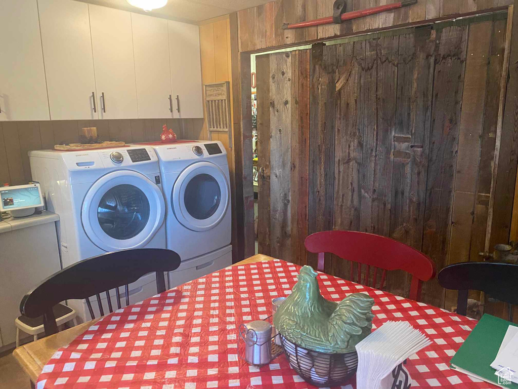 Washroom featuring washer and clothes dryer, wooden walls, and cabinet space