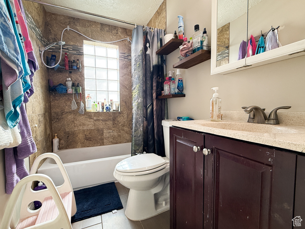 Bathroom featuring toilet, vanity, shower / bath combo, a textured ceiling, and tile patterned flooring