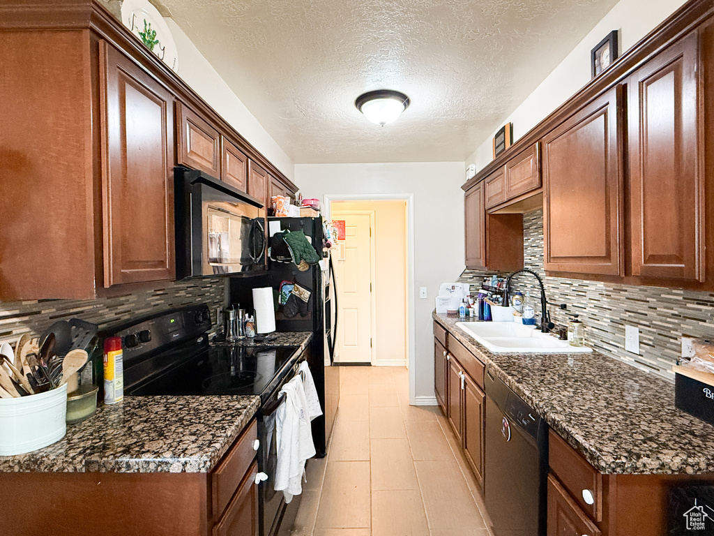 Kitchen featuring a textured ceiling, black appliances, a sink, and tasteful backsplash