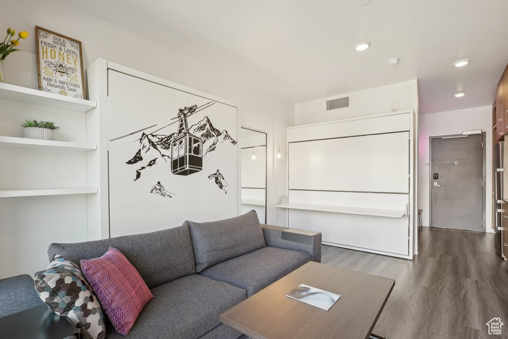 Living room with dark wood-style floors, visible vents, and recessed lighting
