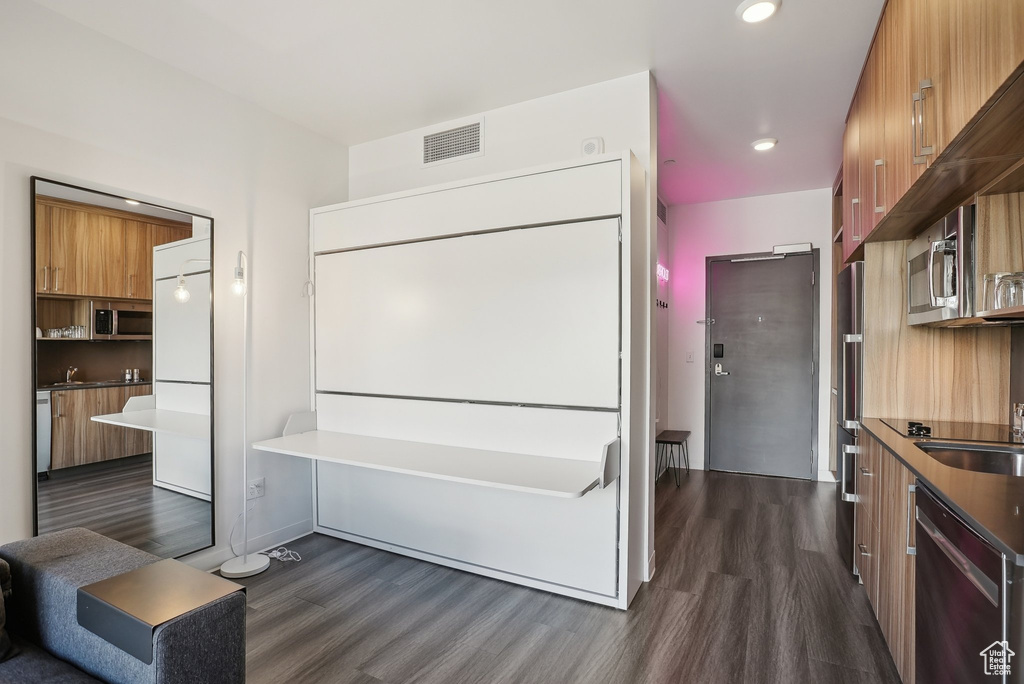 Interior space with dark wood-style floors, visible vents, modern cabinets, appliances with stainless steel finishes, and brown cabinetry