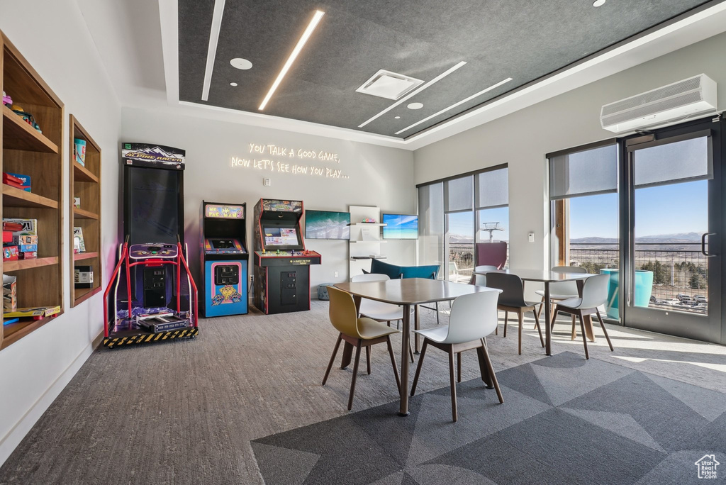 Game room with a tray ceiling, a high ceiling, a wall unit AC, and carpet