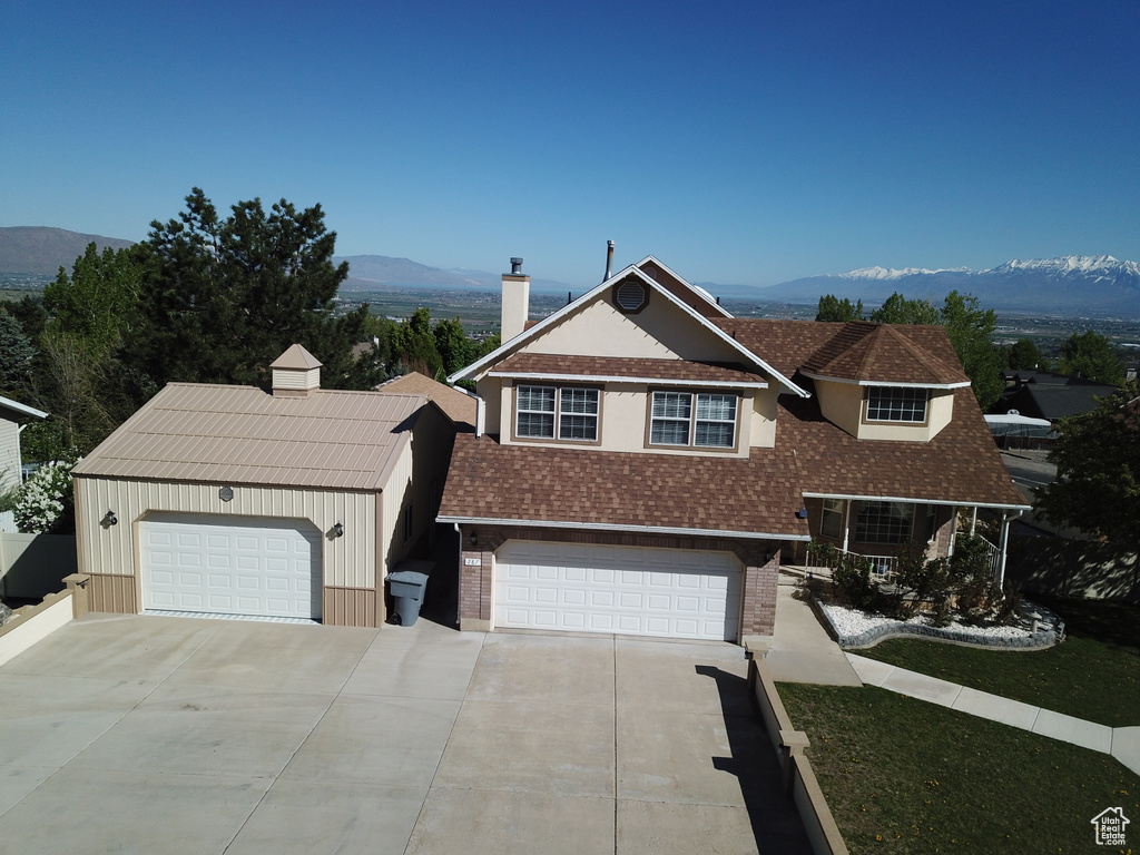 View of front of property featuring a mountain view, a chimney, roof with shingles, and brick siding
