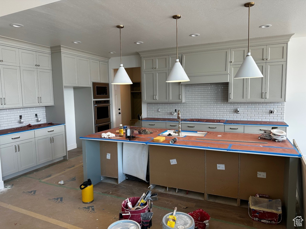 Kitchen featuring a sink, backsplash, appliances with stainless steel finishes, wood counters, and hanging light fixtures