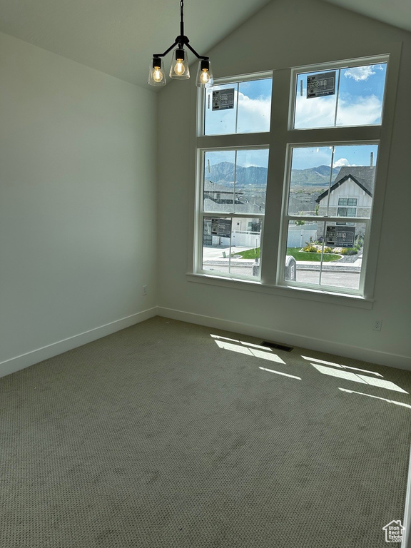Spare room featuring healthy amount of natural light, vaulted ceiling, carpet, and baseboards