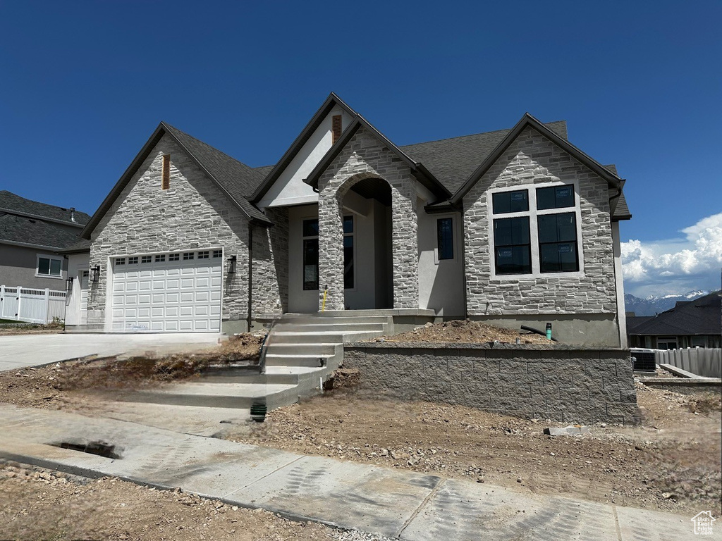 French country style house featuring stone siding, concrete driveway, and a garage