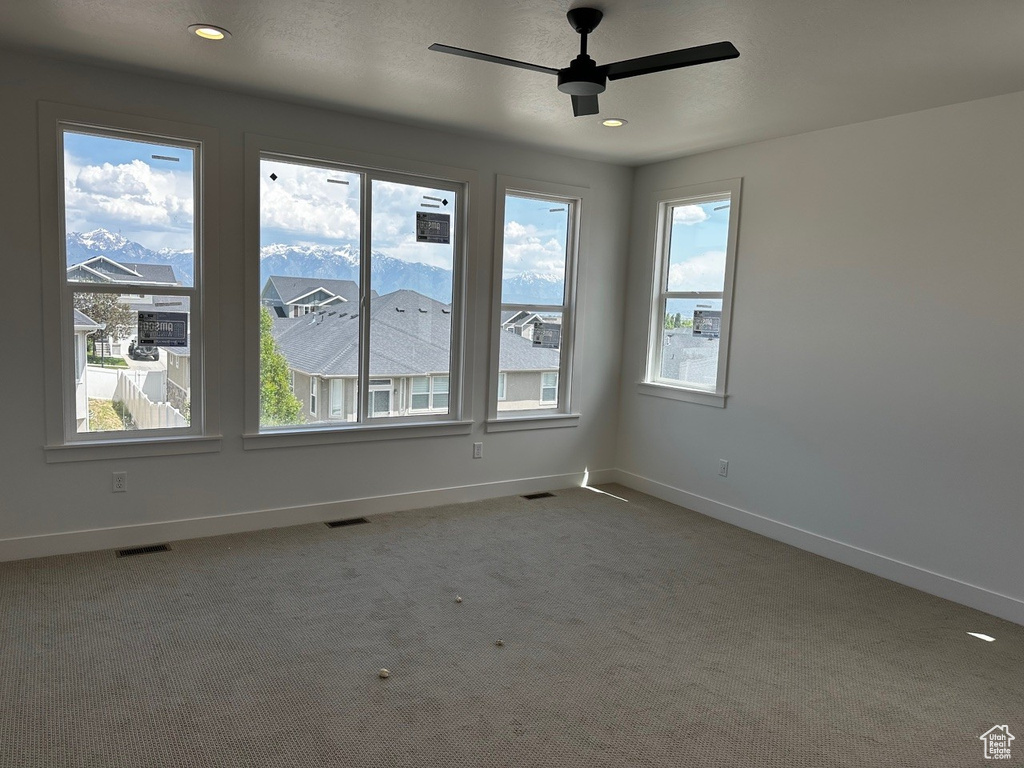Carpeted spare room featuring healthy amount of natural light, a ceiling fan, baseboards, and recessed lighting