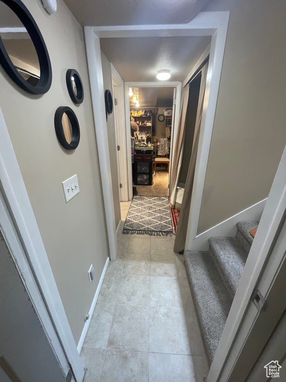 Hall with stairs, baseboards, and light tile patterned floors
