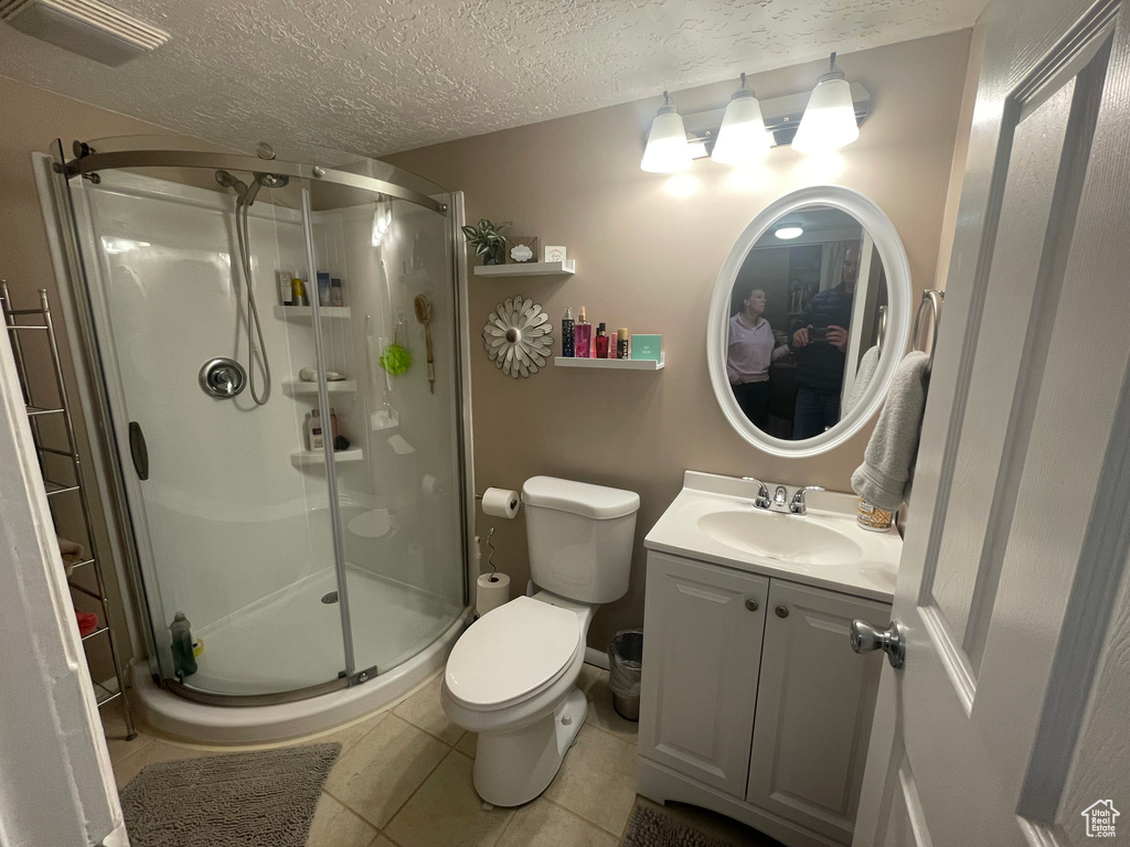 Full bath with a textured ceiling, tile patterned floors, vanity, and a stall shower