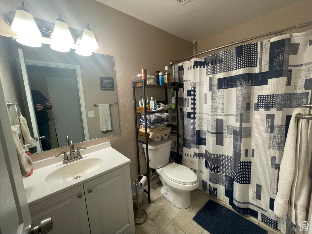 Bathroom with toilet, vanity, a shower with curtain, tile patterned flooring, and a textured wall