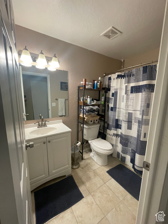 Full bath with tile patterned flooring, vanity, toilet, a textured ceiling, and visible vents