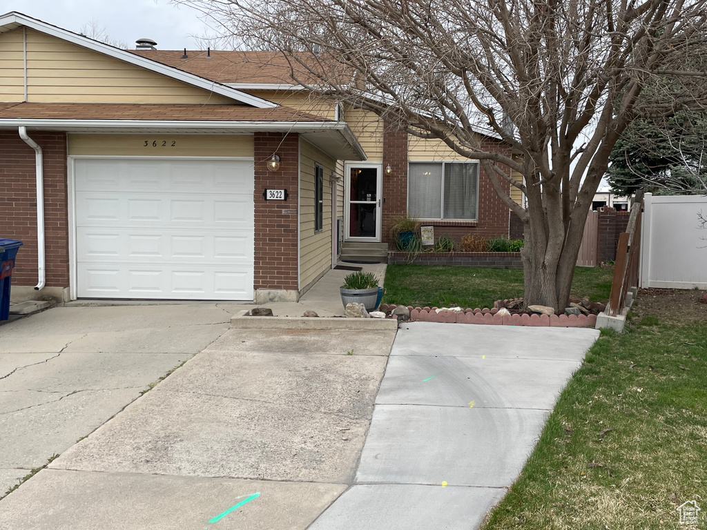 Ranch-style home featuring concrete driveway, fence, entry steps, a front yard, and brick siding