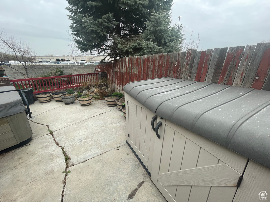 View of patio with a hot tub and fence