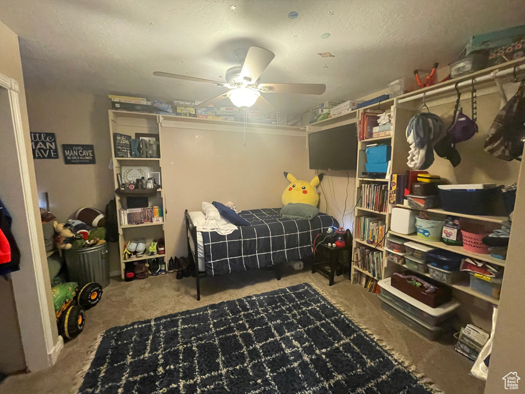 Bedroom featuring a ceiling fan, carpet flooring, and a textured ceiling