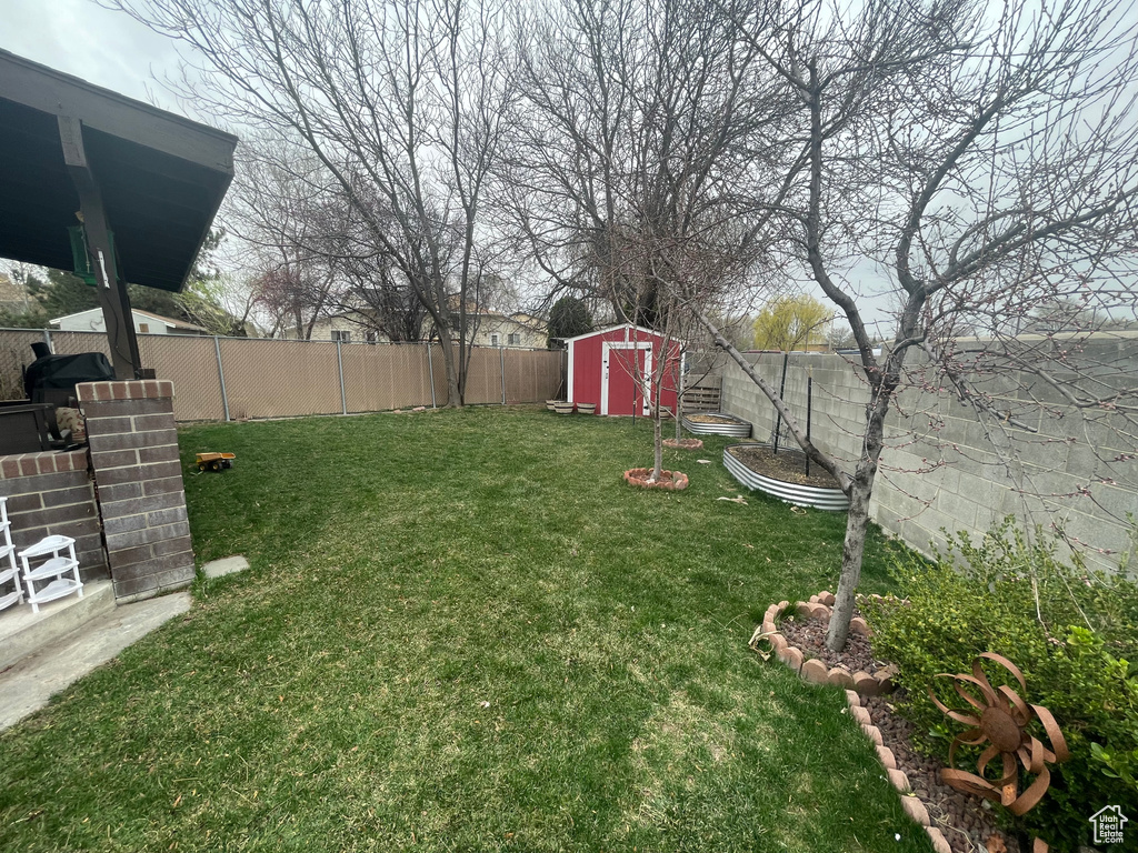 View of yard with a fenced backyard, a shed, and an outbuilding