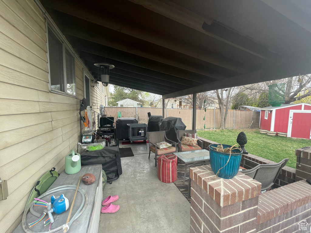 View of patio / terrace featuring an outdoor living space, an outdoor structure, a fenced backyard, a storage unit, and grilling area