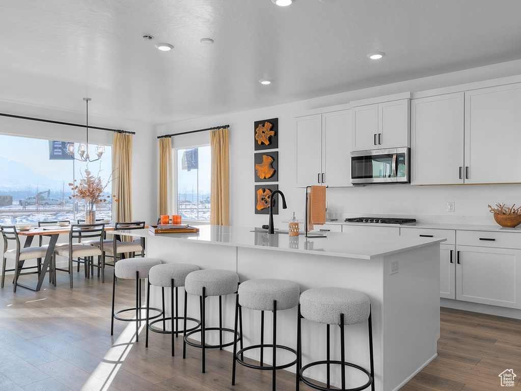 Kitchen with a sink, a notable chandelier, a breakfast bar, stainless steel appliances, and an island with sink