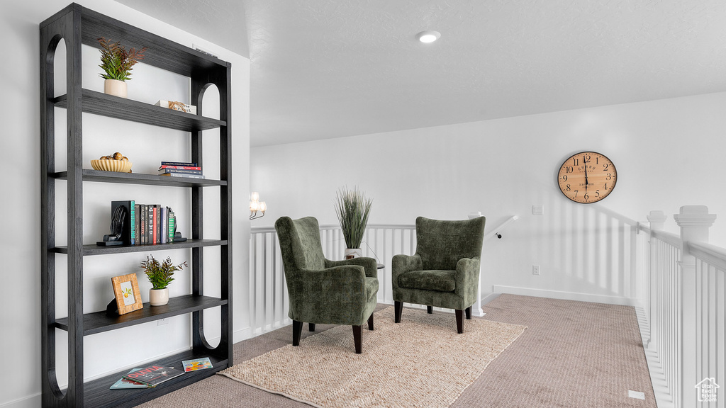 Sitting room with carpet floors, baseboards, and an upstairs landing