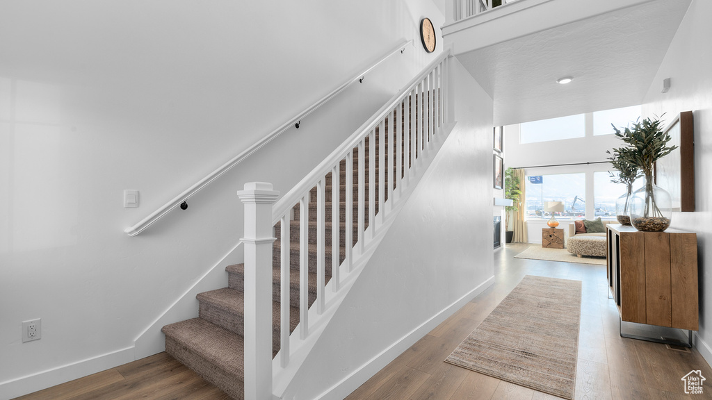 Stairway featuring baseboards, a high ceiling, and wood finished floors