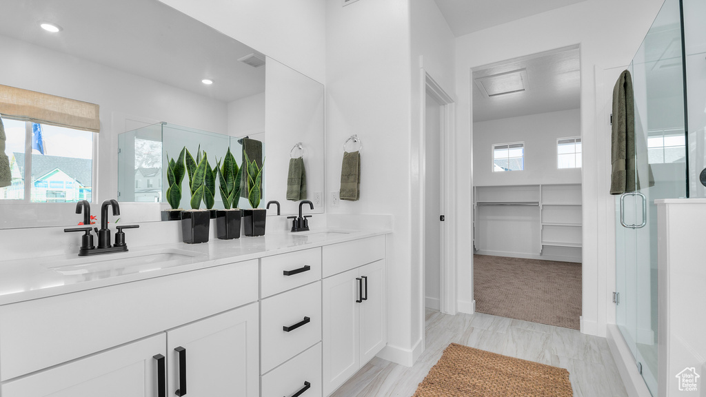 Full bathroom with a sink, a walk in closet, a stall shower, and double vanity