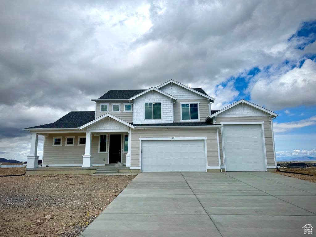 View of front of house featuring a porch, a garage, and driveway