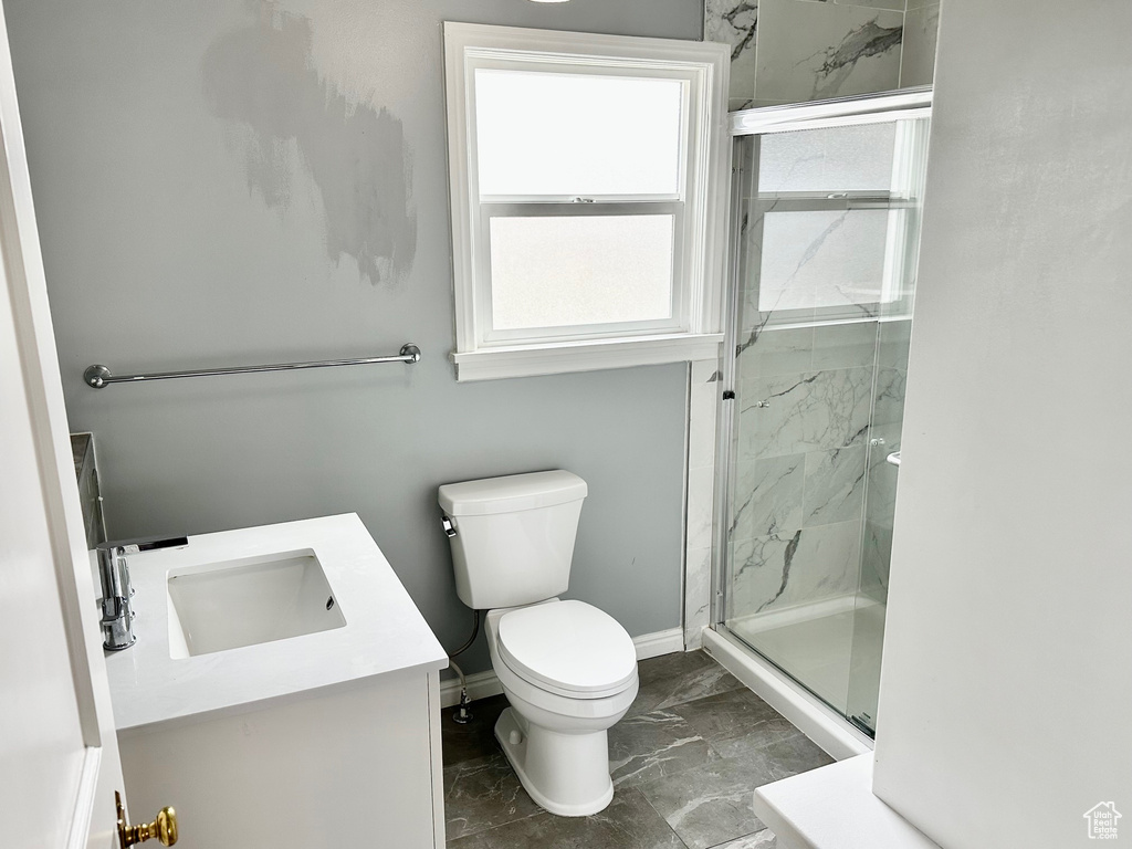 Full bath with toilet, vanity, a marble finish shower, marble finish floor, and baseboards