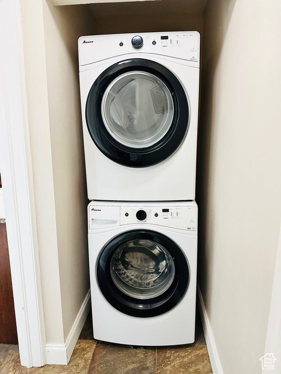 Clothes washing area with baseboards, stacked washer / drying machine, and laundry area
