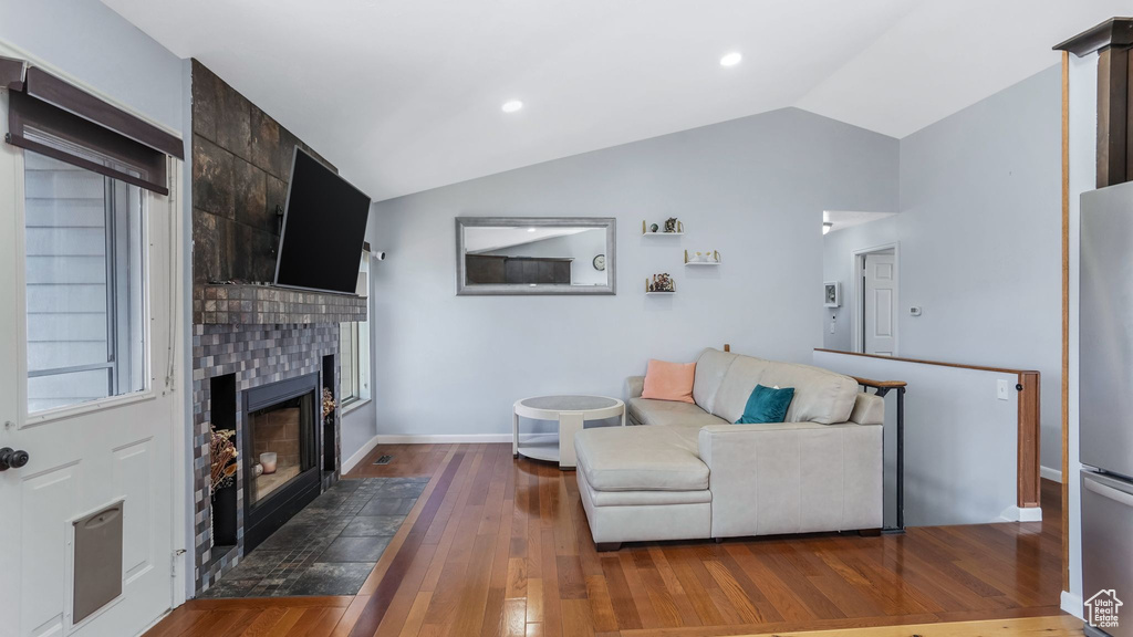 Living room featuring a large fireplace, hardwood / wood-style floors, baseboards, and vaulted ceiling