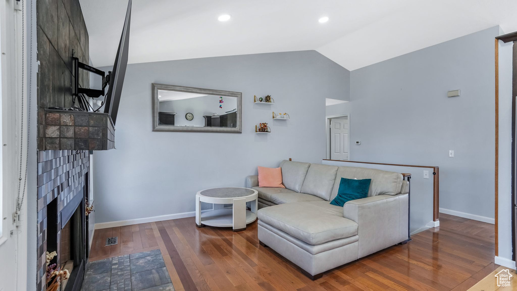 Living area featuring a fireplace with flush hearth, lofted ceiling, baseboards, visible vents, and hardwood / wood-style floors