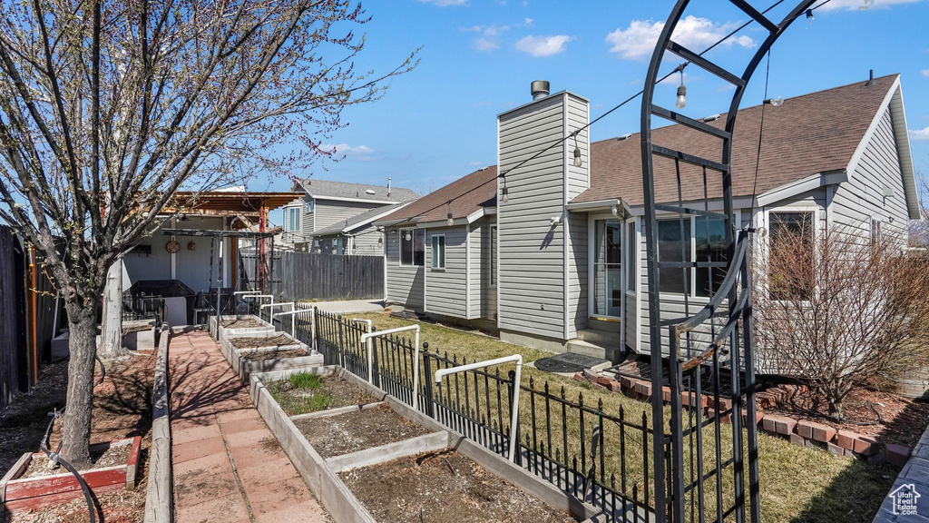 View of side of property with a garden, entry steps, a chimney, a fenced backyard, and a yard