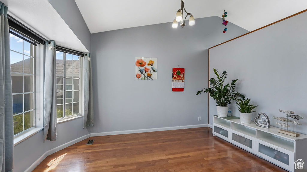 Unfurnished room featuring baseboards, lofted ceiling, and wood finished floors