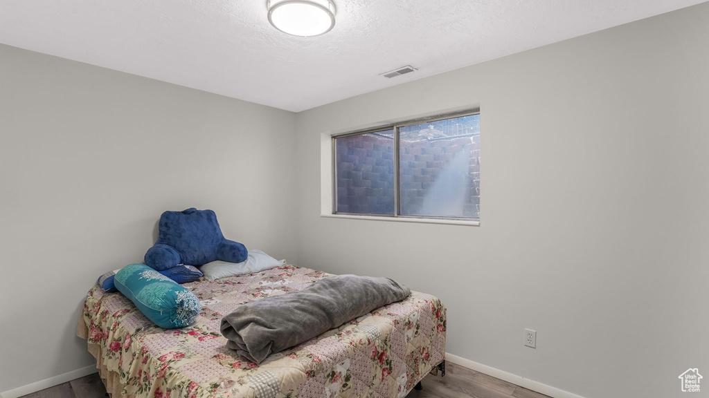 Bedroom with wood finished floors, a textured ceiling, baseboards, and visible vents