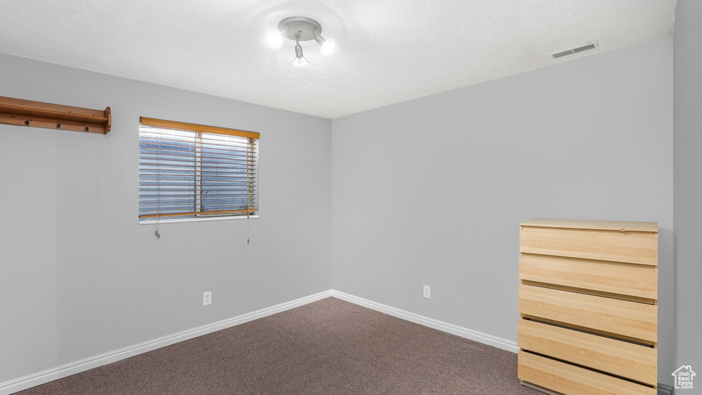 Carpeted spare room featuring baseboards and visible vents