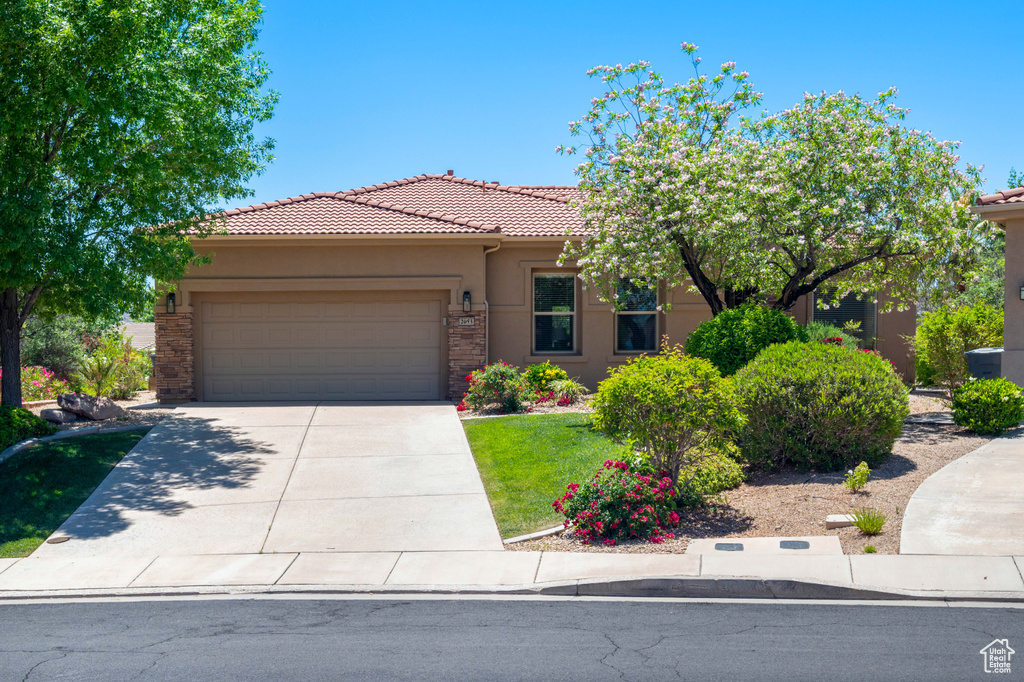 View of front facade with an attached garage, stucco siding, a tiled roof, and concrete driveway